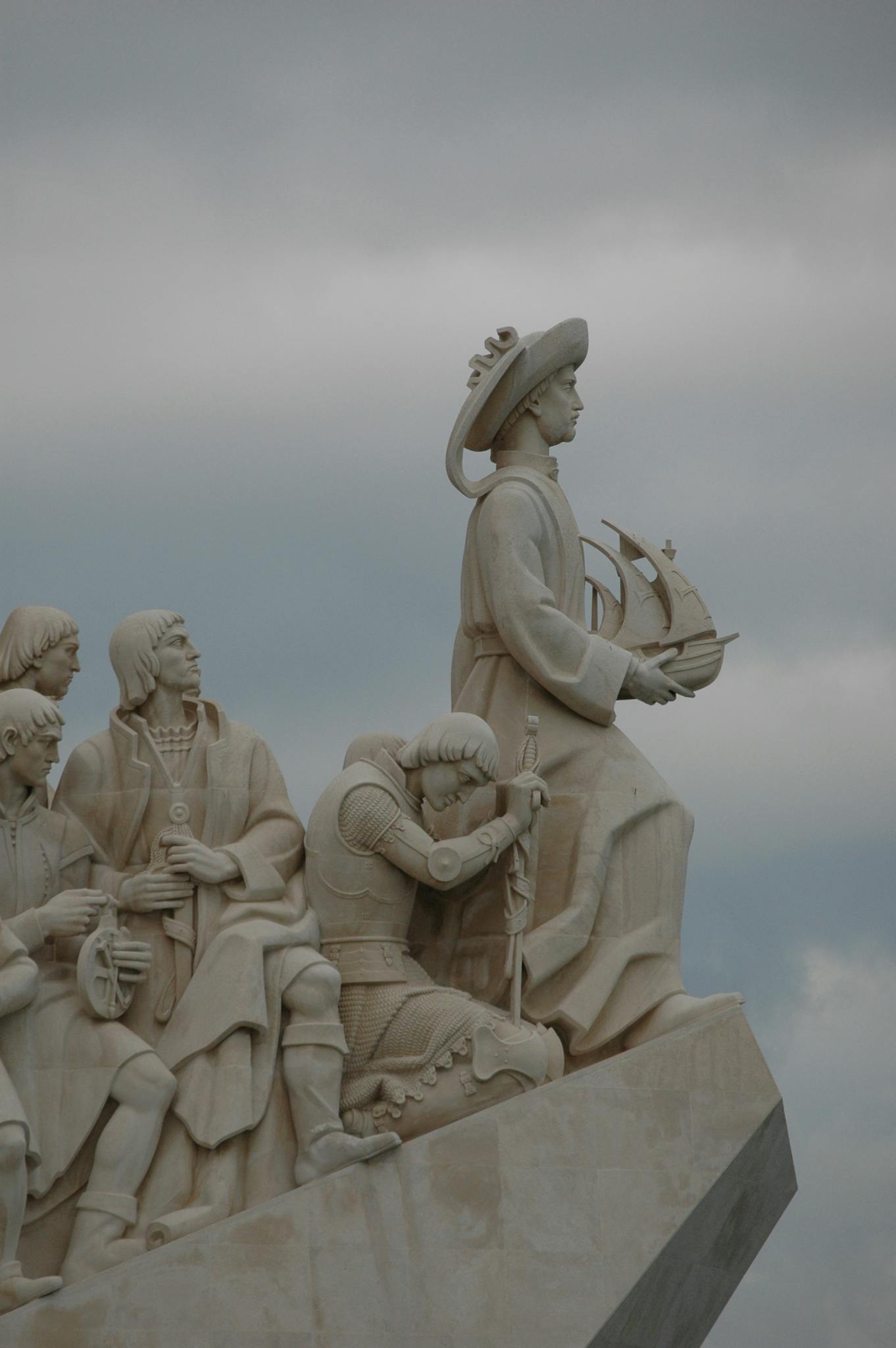 Close-up of the Padrao dos Descobrimentos monument with explorers statues against clouds.